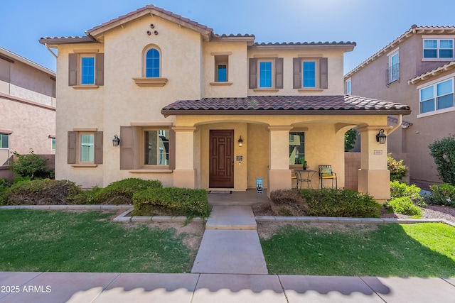 mediterranean / spanish-style house with stucco siding, a tiled roof, and a front lawn