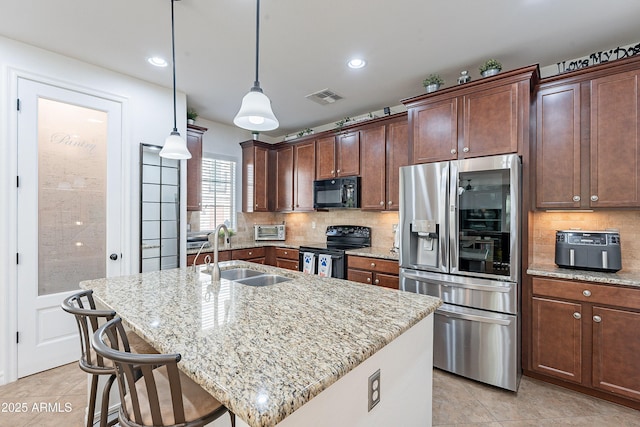 kitchen featuring light stone countertops, tasteful backsplash, visible vents, black appliances, and a sink