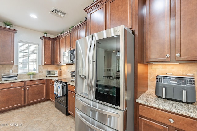 kitchen with light stone countertops, visible vents, stainless steel refrigerator with ice dispenser, black range with electric cooktop, and decorative backsplash
