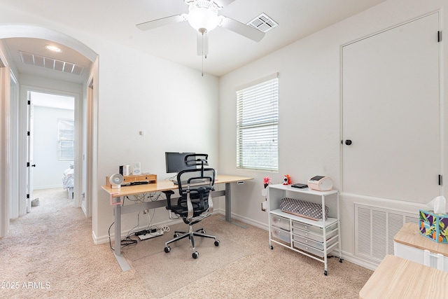 carpeted office space featuring arched walkways, visible vents, and a ceiling fan
