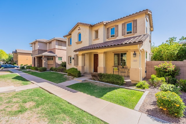 mediterranean / spanish-style home featuring a tiled roof, stucco siding, a porch, fence, and a front lawn
