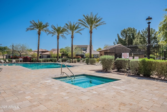 community pool featuring a patio area, fence, and a hot tub