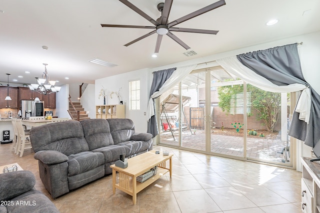 living area with stairway, ceiling fan with notable chandelier, visible vents, and a healthy amount of sunlight