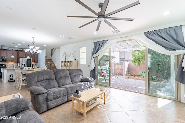 living room featuring ceiling fan with notable chandelier, recessed lighting, visible vents, and stairway