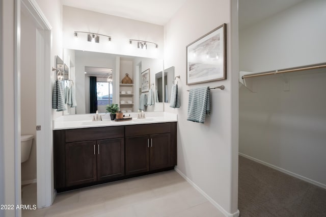 full bathroom with toilet, a sink, baseboards, and double vanity