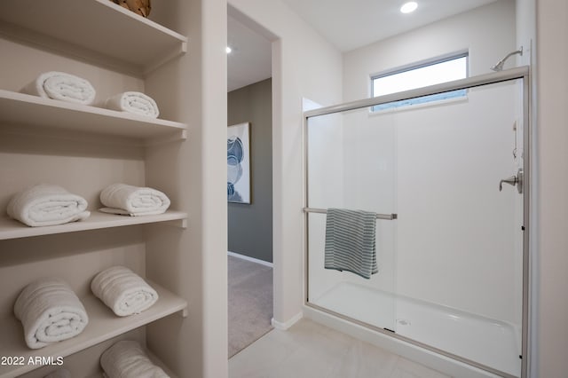 full bathroom with a shower stall and baseboards