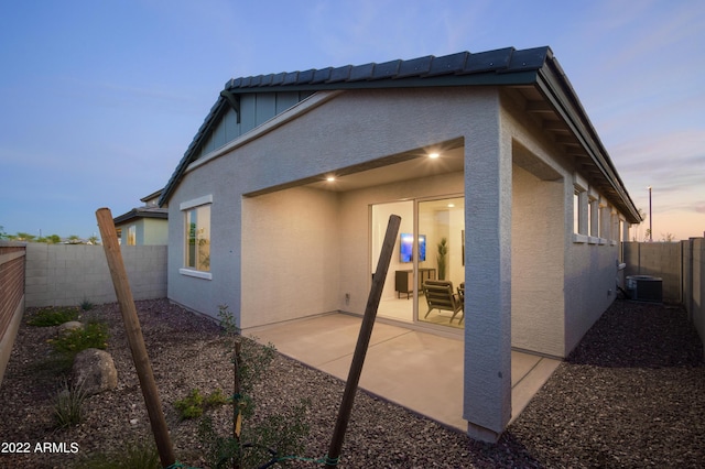 back of property with stucco siding, a fenced backyard, central AC unit, and a patio