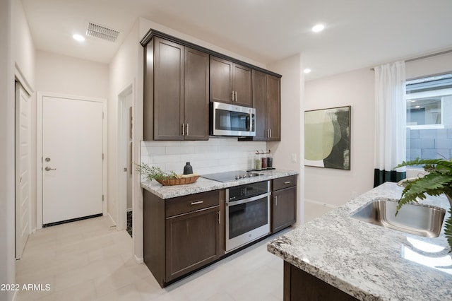 kitchen with visible vents, decorative backsplash, appliances with stainless steel finishes, dark brown cabinetry, and a sink