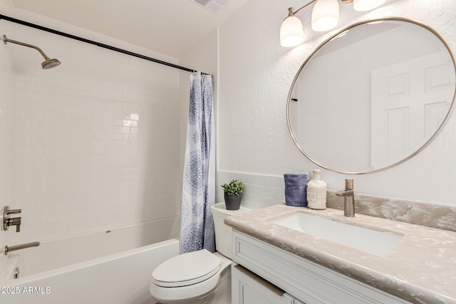 bathroom featuring visible vents, a textured wall, shower / bathtub combination with curtain, toilet, and vanity