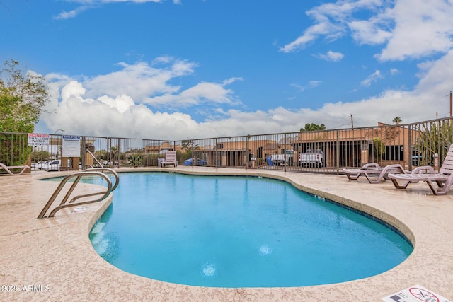 pool with a patio area and fence