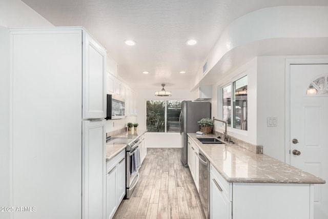 kitchen with light stone counters, visible vents, appliances with stainless steel finishes, white cabinetry, and a sink