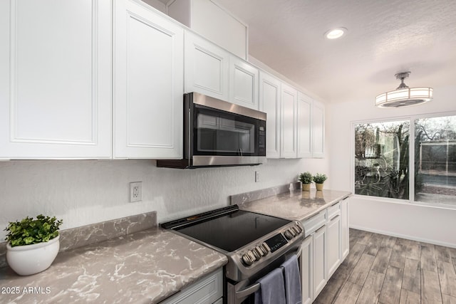 kitchen featuring light stone counters, recessed lighting, wood finished floors, white cabinetry, and appliances with stainless steel finishes