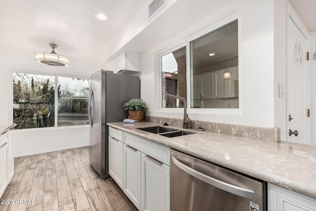 kitchen with wood finish floors, visible vents, appliances with stainless steel finishes, white cabinets, and a sink