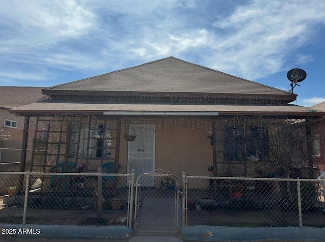 view of front of property with a gate, fence, and stucco siding