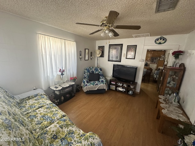 bedroom with visible vents, a textured ceiling, and wood finished floors