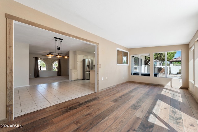 unfurnished living room featuring ceiling fan, a healthy amount of sunlight, lofted ceiling, and light wood-type flooring