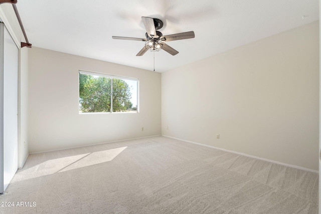 spare room featuring light colored carpet and ceiling fan