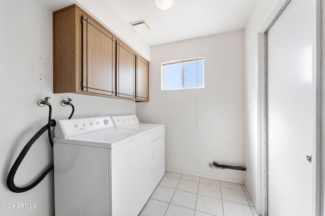 laundry area featuring light tile patterned flooring, washing machine and dryer, and cabinets