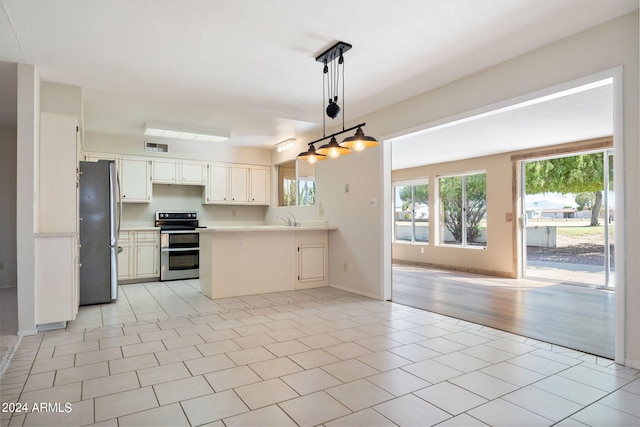 kitchen featuring appliances with stainless steel finishes, kitchen peninsula, decorative light fixtures, and light tile patterned floors