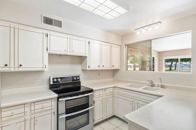 kitchen with electric stove, a textured ceiling, sink, and light tile patterned floors