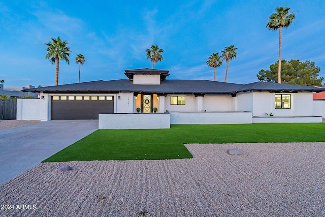 prairie-style home featuring a front lawn and a garage