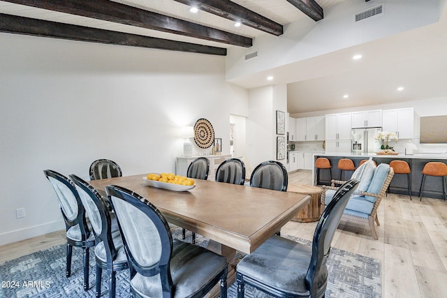 dining area featuring beam ceiling, washing machine and dryer, and light hardwood / wood-style flooring