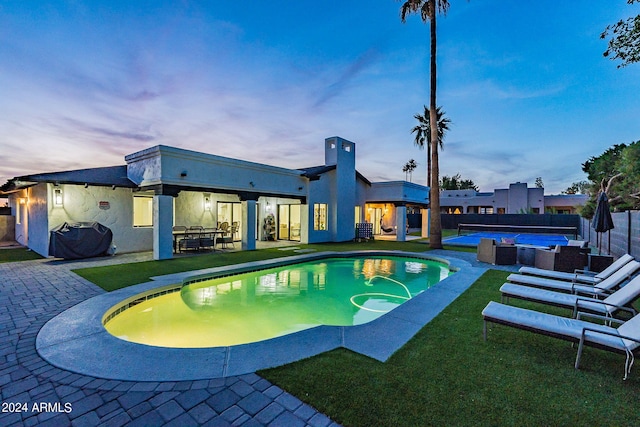 pool at dusk with an outdoor living space, a grill, and a patio area