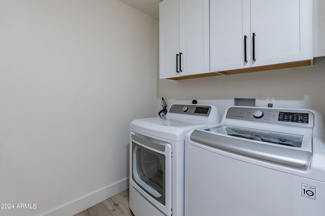 washroom featuring cabinets, independent washer and dryer, and light hardwood / wood-style flooring