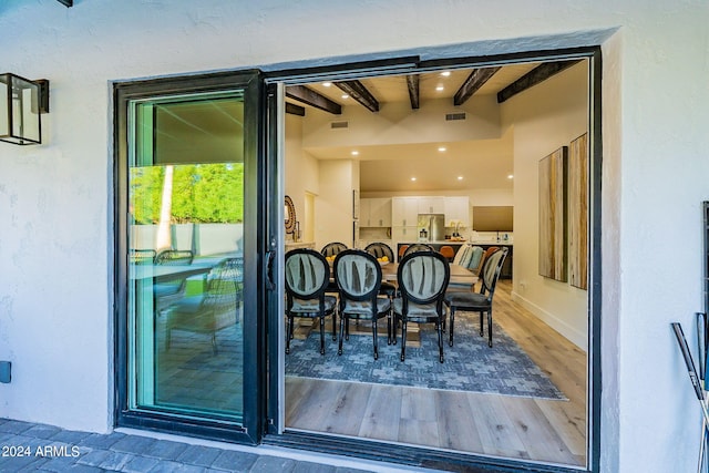 exterior space featuring white cabinets, stainless steel fridge with ice dispenser, beamed ceiling, and hardwood / wood-style flooring