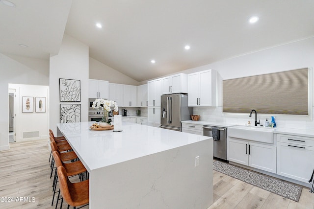 kitchen featuring stainless steel appliances, a kitchen island, white cabinetry, and sink