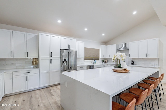 kitchen featuring white cabinets, a center island, a kitchen bar, and appliances with stainless steel finishes