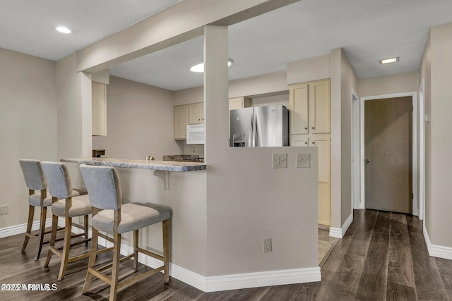 2800 N Saddleback Way Unit 2, Flagstaff, AZ 86004 - kitchen featuring a breakfast bar area, baseboards, white microwave, and stainless steel fridge with ice dispenser