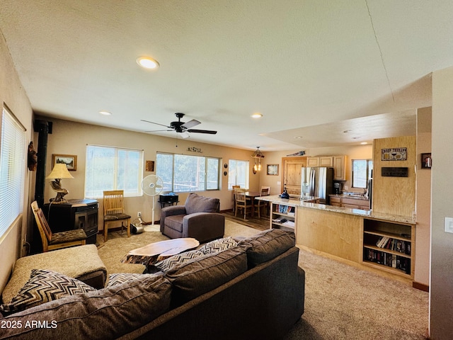 living area with baseboards, ceiling fan, light colored carpet, recessed lighting, and a wood stove