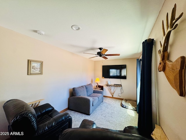 carpeted living area featuring ceiling fan and baseboards