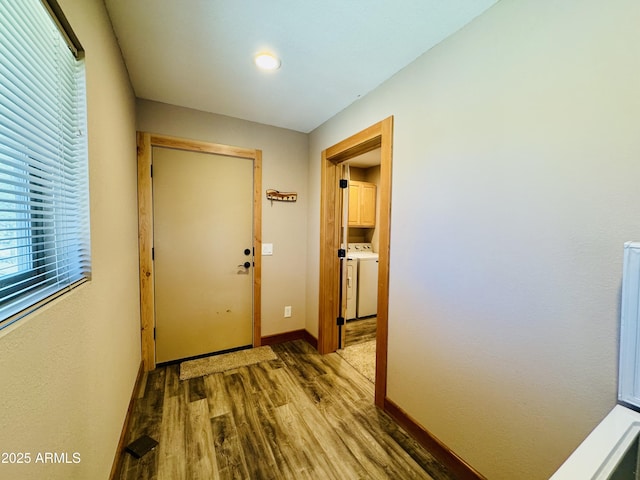 doorway to outside with separate washer and dryer, baseboards, and wood finished floors