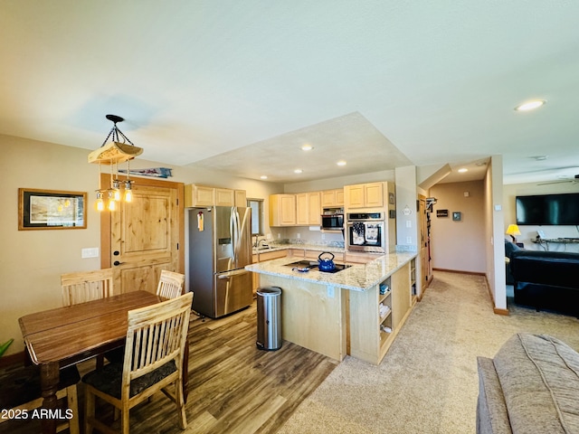 kitchen featuring light brown cabinets, open floor plan, recessed lighting, appliances with stainless steel finishes, and a sink