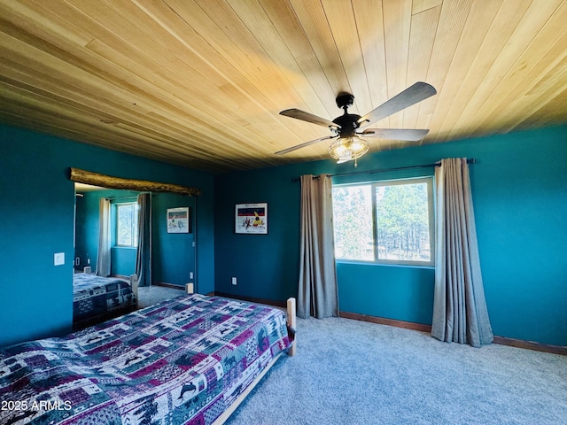 carpeted bedroom with baseboards, multiple windows, wood ceiling, and a ceiling fan