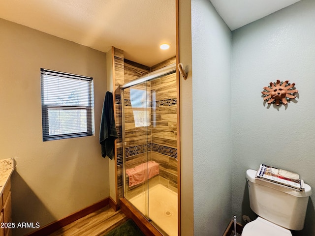 bathroom featuring a shower stall, baseboards, toilet, wood finished floors, and vanity