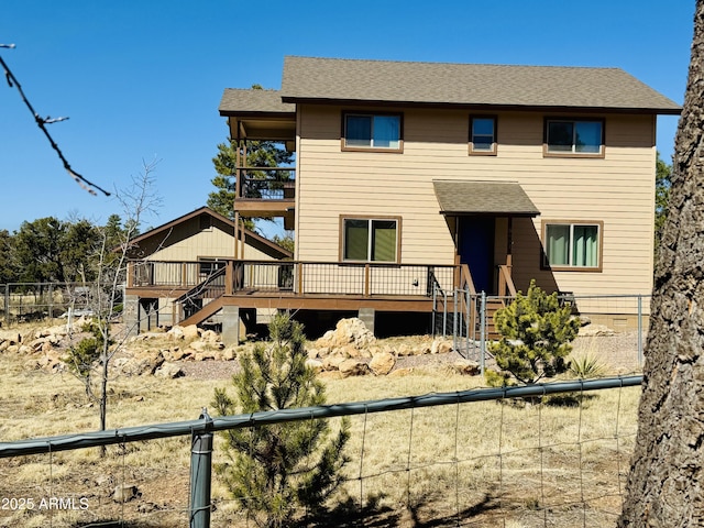 view of front of home with stairway, a shingled roof, a wooden deck, and fence