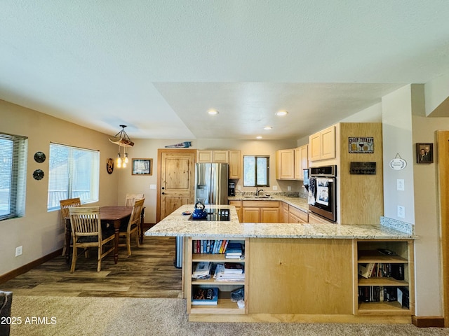 kitchen featuring light stone counters, light brown cabinets, open shelves, appliances with stainless steel finishes, and a wealth of natural light