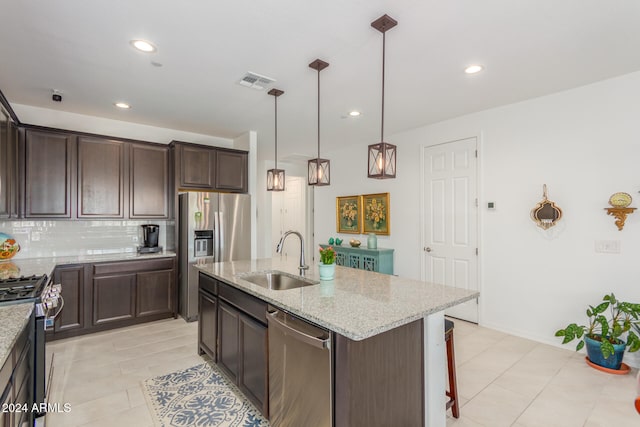 kitchen featuring tasteful backsplash, appliances with stainless steel finishes, light stone countertops, sink, and a kitchen island with sink