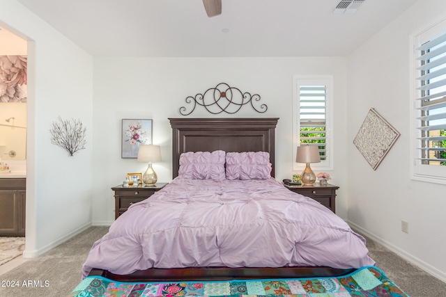 bedroom with ensuite bath, light carpet, and ceiling fan