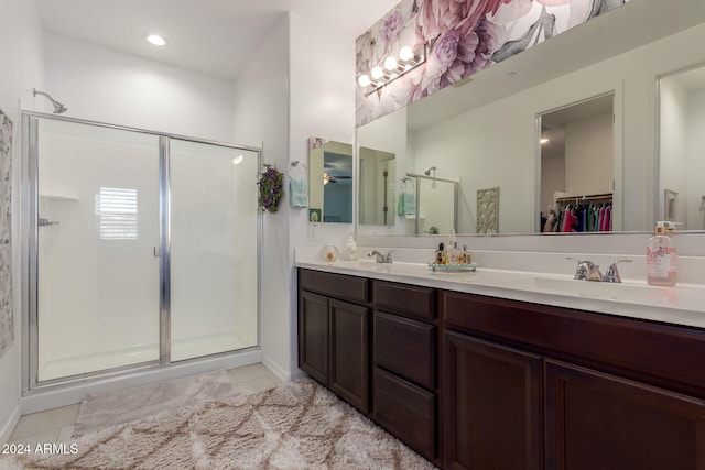 bathroom with a shower with door, vanity, and tile patterned flooring