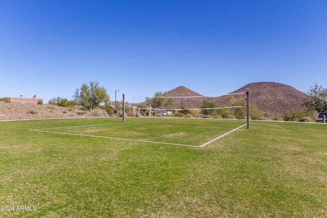 view of community with a mountain view, volleyball court, and a yard