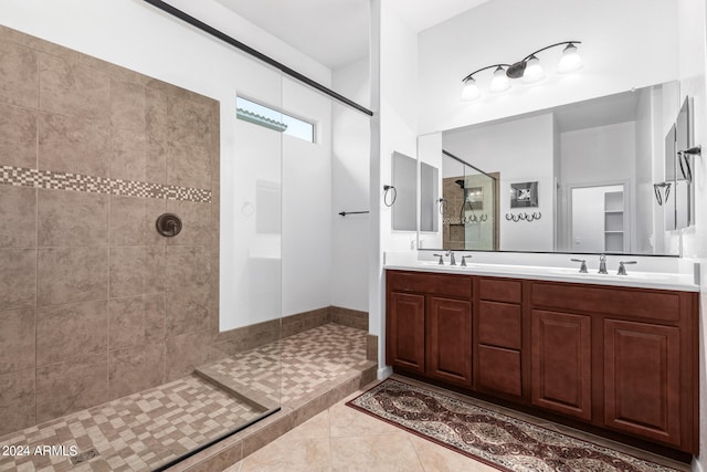 bathroom with dual vanity, tiled shower, and tile patterned flooring