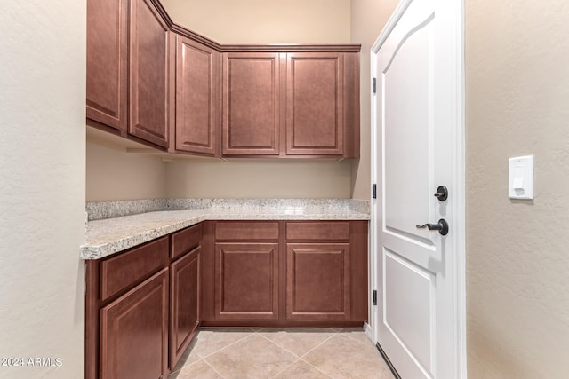 kitchen featuring light tile patterned floors and light stone counters