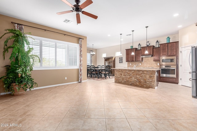 kitchen featuring ceiling fan with notable chandelier, appliances with stainless steel finishes, hanging light fixtures, custom range hood, and tasteful backsplash