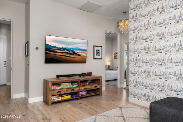 living room featuring a chandelier, baseboards, visible vents, and light wood finished floors