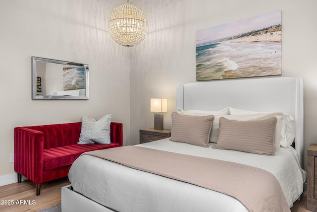 bedroom featuring a notable chandelier, baseboards, and wood finished floors