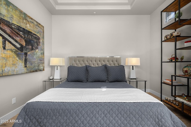 bedroom featuring a raised ceiling, dark wood finished floors, and baseboards